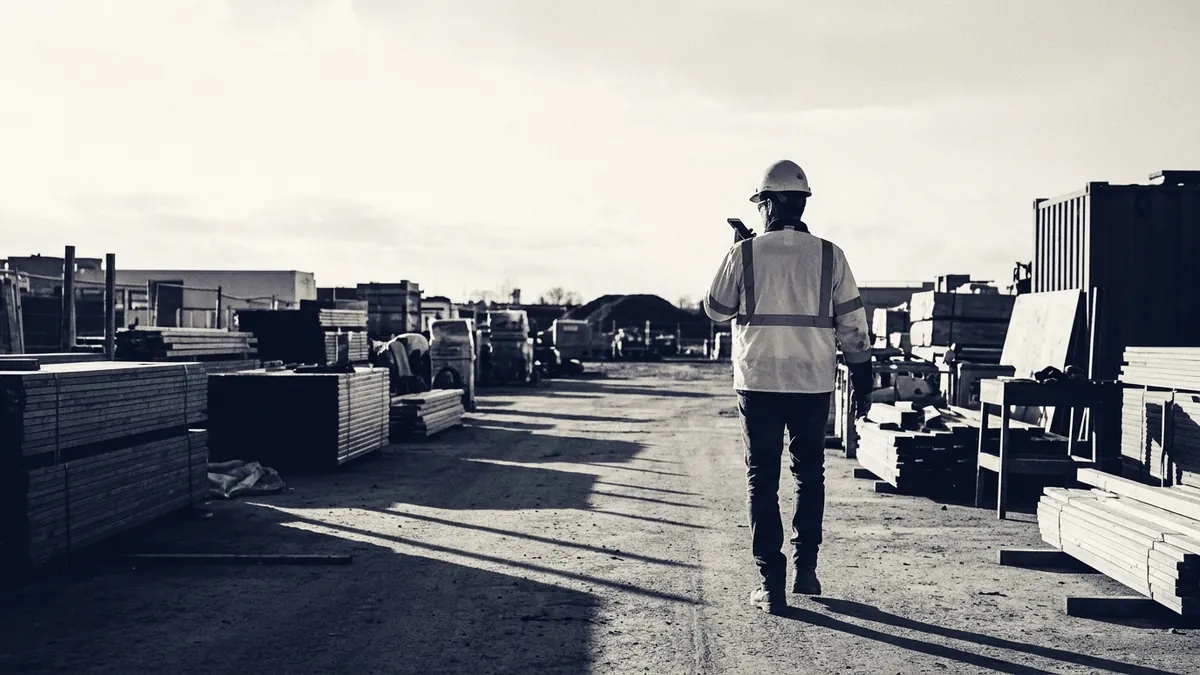 A superintendent walking a materials yard dictating into a phone at end of shift